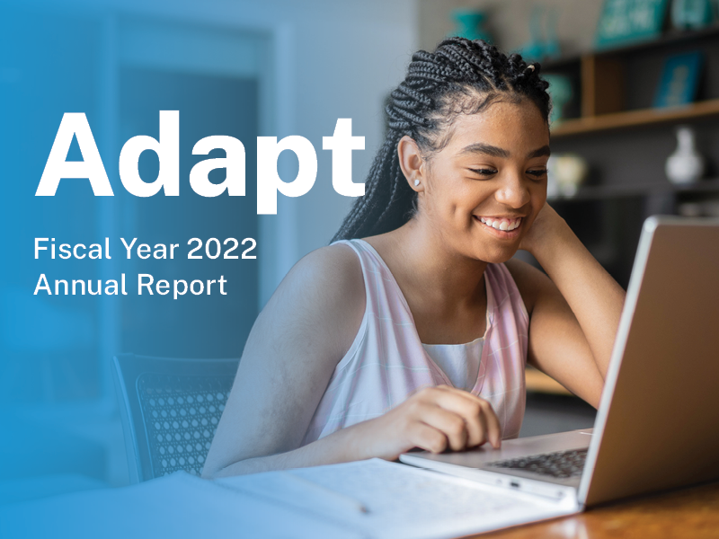 Young Black woman smiling at computer screen with text that reads Adapt: Fiscal Year 2022 Annual Report