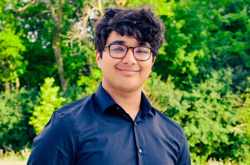 Photograph Of College Possible Student, Areeb Wearing A Long Sleeved Blue Shirt And Smiling For The Camera
