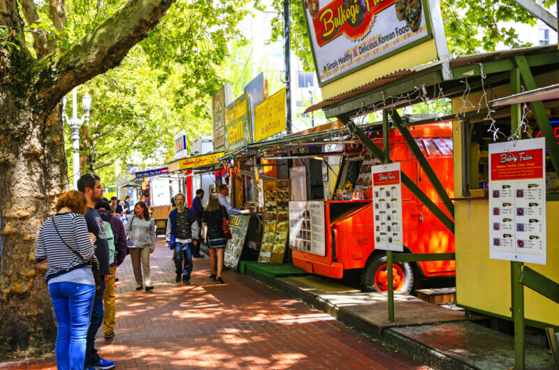People Line The Sidewalk On A Sunny Day To Order From The Food-truck Vendors Lining The Street Curb In Downtown Portland, Oregon.