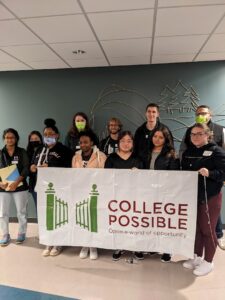 A group photo of students and college possible team members holding a "College Possible" banner on a campus visit.