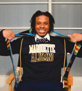 Rashad proudly displays graduation stoles over a Marquette University sweatshirt