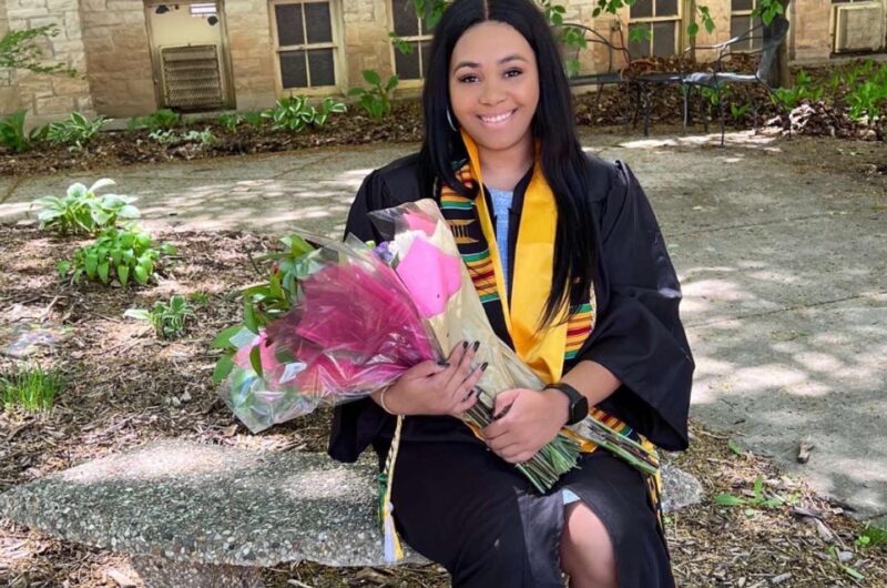 Sinyetta Holding A Bouquet Of Flowers In A Graduation Gown