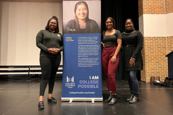 Panelists Standing Next To Retractable Banner Showing A College Possible Student And A Quote.
