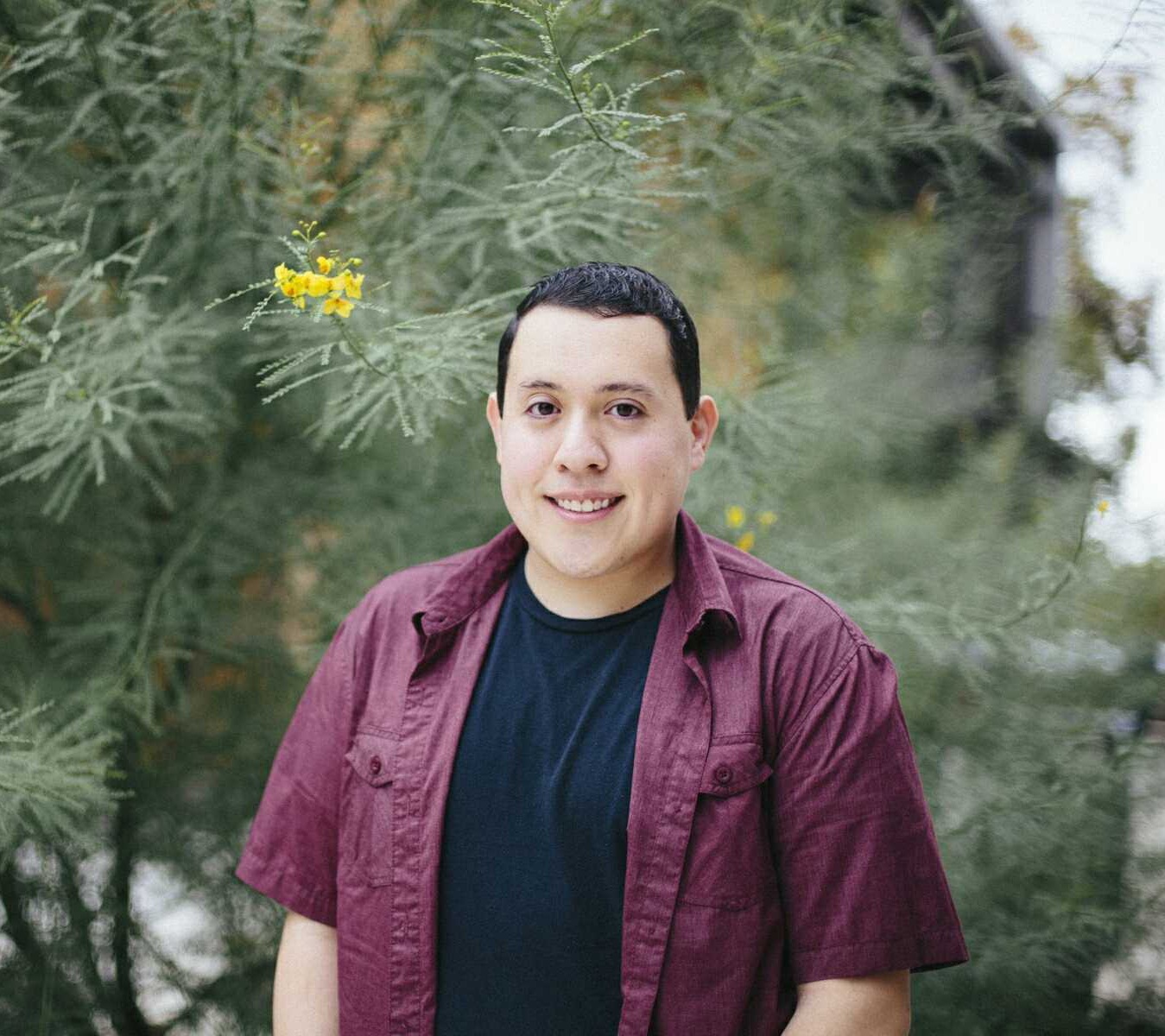 Young man smiling in front of some trees