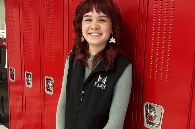 Photo Of Missy Wearing A College Possible Vest And Standing In Front Of Red Lockers