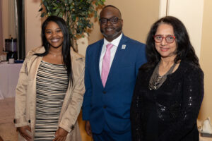 Three professionally dressed individuals smiling at the camera