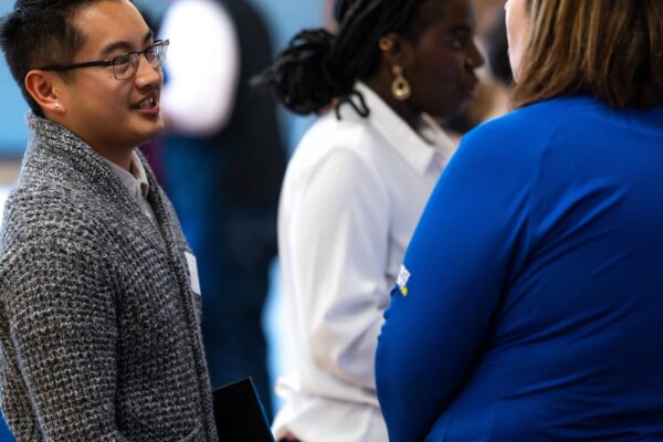 Two Professionals Engaged In A Conversation At A Networking Event.