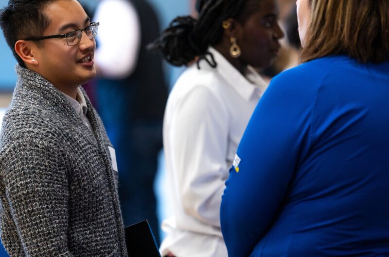 Two Professionals Engaged In A Conversation At A Networking Event.