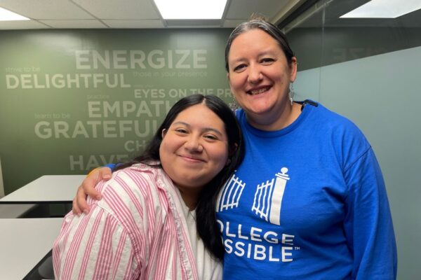 Student Dressed In A Pink And White Striped Shirt Smiling And Giving A Side Hug To Her College Coach.