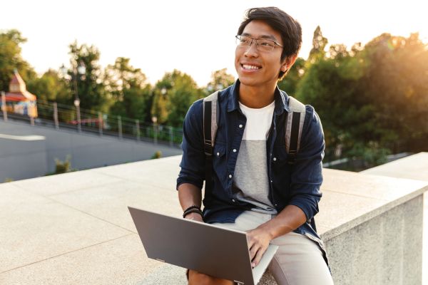 Student smiling as he uses his laptop