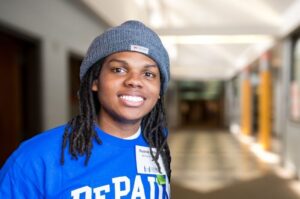 A student in a blue DePaul University shirt poses smiling.