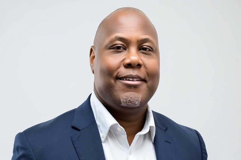 Headshot of Thomas Bookman wearing a white button up and blue suit jacket.