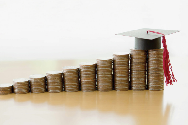 Stacks of coins arranged in ascending order with a graduation cap placed on the tallest stack.