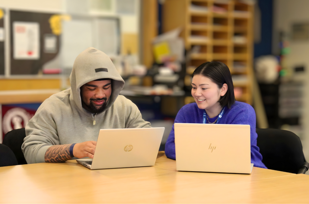 Dominic and his advisor Katie, sit side by side at the table with their laptops. Katie is helping Dominic with his scholarship application.